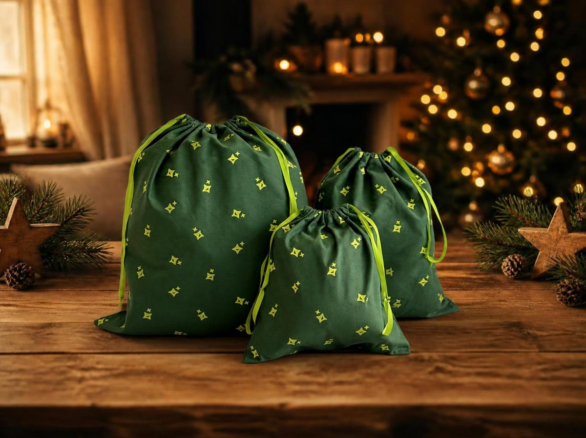 Three " MagicHolz" cotton gift bags in sizes S, M, and L on a wooden table with a festive Christmas atmosphere